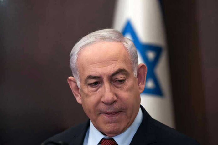 2415917203-1 Man in suit with Israeli flag in background.