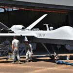 Iran’s Bold Gamble Hits U.S. Nerve Military drone being serviced by ground crew outside a hangar
