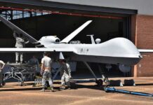 Iran’s Bold Gamble Hits U.S. Nerve Military drone being serviced by ground crew outside a hangar