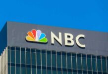NBC logo displayed on a corporate building against a blue sky