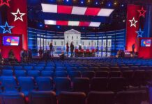 Senate Dem Debate Labeled A Disaster – Can’t Answer ONE Question Debate stage with red and blue lighting and empty audience seats