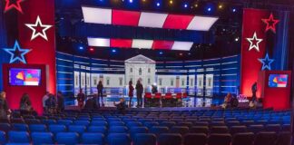 Debate stage with red and blue lighting and empty audience seats