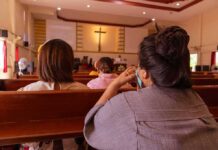 Knifeman STABS Woman Praying During Mass people seated in church pews facing a cross