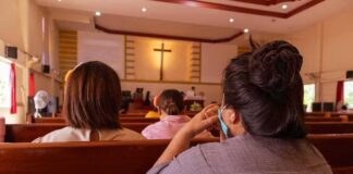 people seated in church pews facing a cross