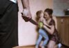 Man holding knife as woman shields child in kitchen