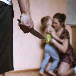 Bourdain Protégé Jailed — What Happened? Man holding knife as woman shields child in kitchen
