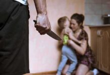 Bourdain Protégé Jailed — What Happened? Man holding knife as woman shields child in kitchen