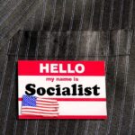 Socialist Leader Living With PARENTS in Million-Dollar House Name tag on a pinstripe suit jacket pocket