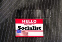 Socialist Leader Living With PARENTS in Million-Dollar House Name tag on a pinstripe suit jacket pocket