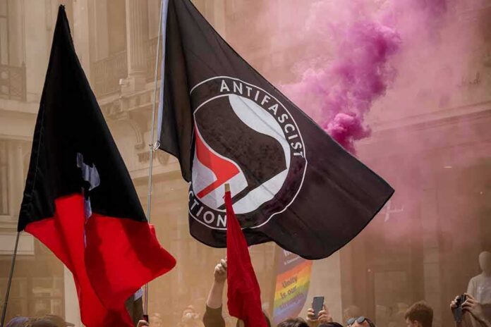 protesters with antifascist flags and purple smoke