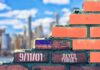 Brick wall with American flag and memorial text against city skyline