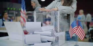 Person casting a ballot into a clear box at a polling station