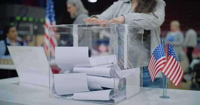Person casting a ballot into a clear box at a polling station