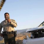 Police officer at crash scene near damaged white car
