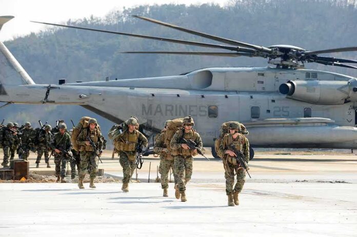 shutterstock_1123252001-2 Soldiers disembark and walk past a large military helicopter