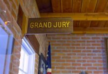 Clancy Juror ATTACKED For Being Republican Grand jury sign in a brick-walled hallway