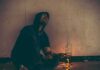 STUDY: Death Rates For Young Adults Surge 71% Person in hoodie sitting on floor with drug paraphernalia