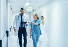 Doctor and nurse walking in a hospital corridor reviewing a tablet