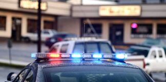 Police car with flashing red and blue lights in a parking lot