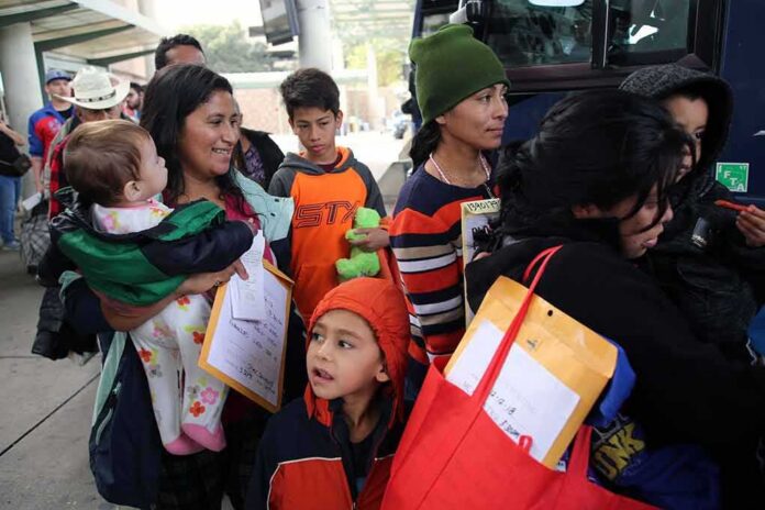 shutterstock_1260576619 Group of people with children waiting in line near a bus
