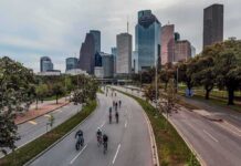 Cyclists on a curved urban road with a modern city skyline