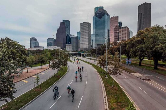 Cyclists on a curved urban road with a modern city skyline