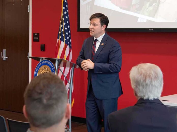 Speaker in a navy suit addressing an audience at a podium