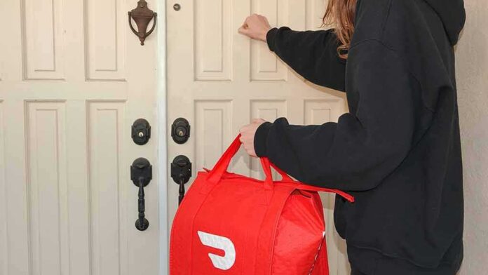Food delivery worker knocking on a front door with a red insulated bag