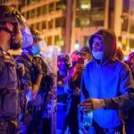 Protesters Hunt FBI Director, Chaos at Funeral Protesters talk with police officers at night in city street