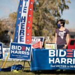 Volunteer at outdoor campaign table with Biden Harris signs