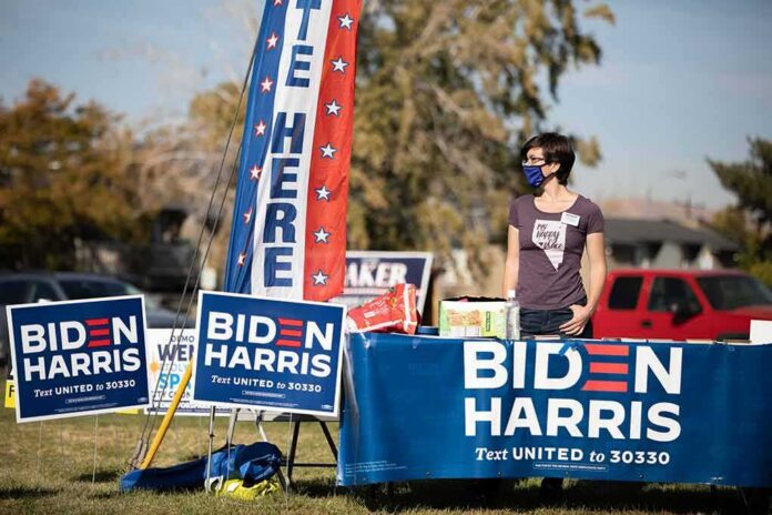 shutterstock_1847496511 Volunteer at outdoor campaign table with Biden Harris signs