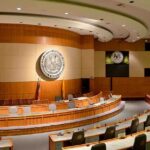 Aging Senator Absent Since Being Found Unconcious! Interior view of a government chamber with wooden paneling and seating