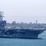 Senators Demand Investigation Into Conditions Aboard U.S. Warship Aircraft carrier escorted by a tugboat in a harbor