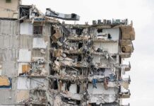 Partially collapsed apartment building with exposed rooms and debris