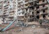 Damaged apartment building behind a playground slide