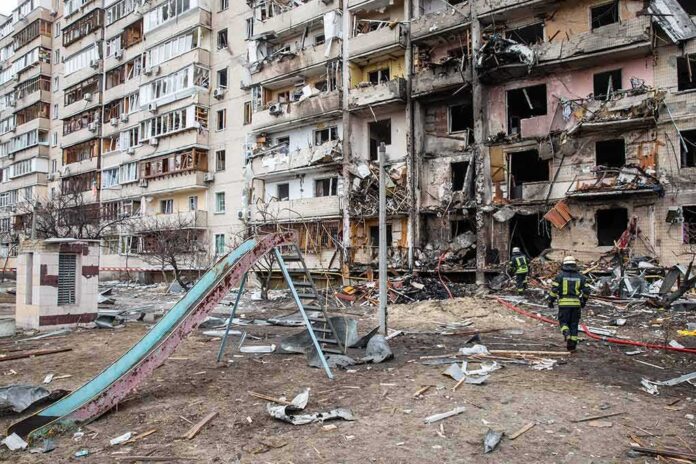 shutterstock_2129012939 Damaged apartment building behind a playground slide