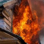 Fireworks Hoard Turns Street Into War Zone House on fire with flames pouring from a window