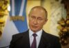Vladimir Putin speaking at a podium with microphones