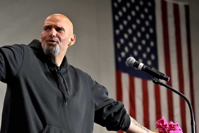 shutterstock_2206788181 Bald man speaking at a microphone with a U.S. flag in the background