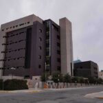 FBI Informant REVEALED – Infiltrated Newsom! Modern concrete and dark glass government building on a cloudy day