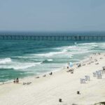 Violent Brawl Over Beach Lounge Leaves Tourist Dead Sandy beach with turquoise waves and a long pier