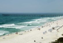 Violent Brawl Over Beach Lounge Leaves Tourist Dead Sandy beach with turquoise waves and a long pier