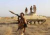 soldier carrying rocket-propelled grenade launcher in front of armored vehicle