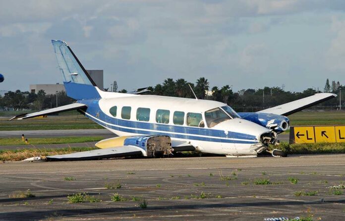 Damaged blue and white small airplane on an airport runway