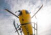 News Chopper Plunges Into Street – City Stunned! Yellow helicopter seen from below with spinning rotor against a bright sky