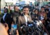 Zohran Mamdani speaks at a press conference; Julia Bacha is visible among the crowd
