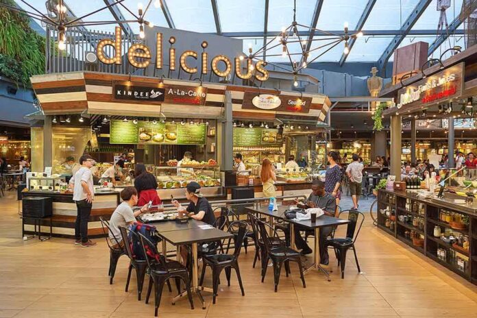 Food court with diners seated at tables near market-style food stalls