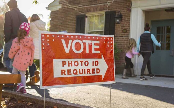 shutterstock_512254585-1 Red voting sign with arrow near people entering a polling place