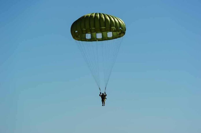 shutterstock_562669618-1 Parachutist descending under a green round canopy