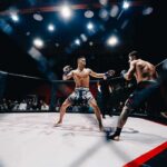 Two MMA fighters square off in a caged octagon